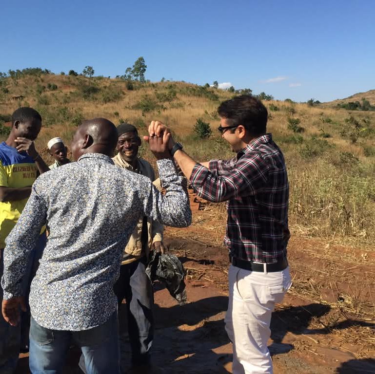 PMEye consultant shaking hands with community members on open ground in Zomba district, Malawi