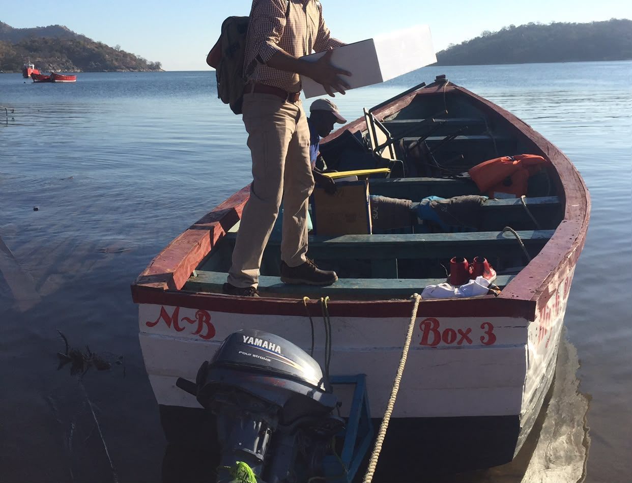 PMEye consultant carrying survey equipment aboard a boat at the lakeshore in Malawi